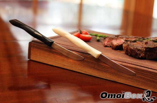 two steak knives magnetically sticking to wooden steak board