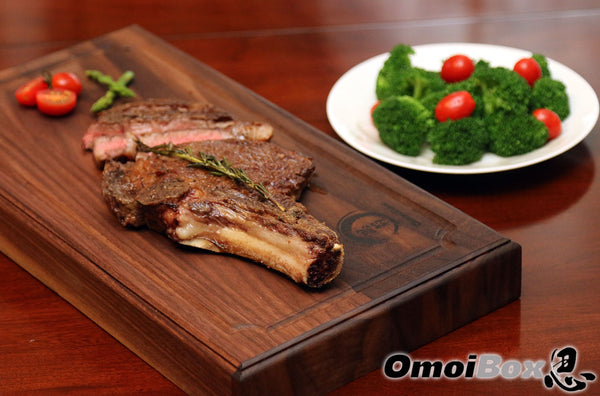 American wagyu beef on steak serving board. side of broccoli and cherry tomatoes 